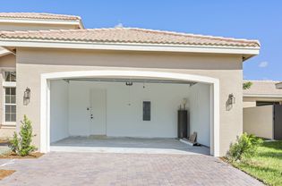 garage and driveway of light beige home with the garage door open and inside empty