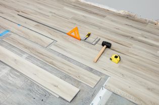 Vinyl plank flooring being installed with tools laid on ground