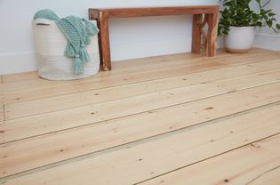 Hardwood finished flooring with bench, bag with green woven fabric and houseplant