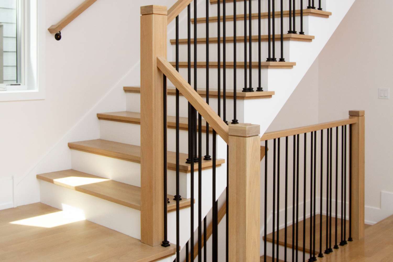 Escalier blanc avec un garde-corps en bois et métal sur des marches en bois gros plan