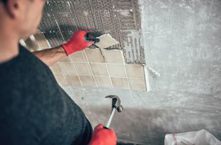 Person removing tile from the wall