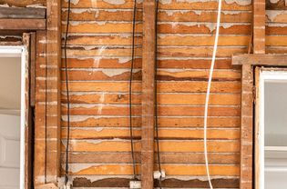 Lath and plaster walls exposed in home renovation with wires hanging