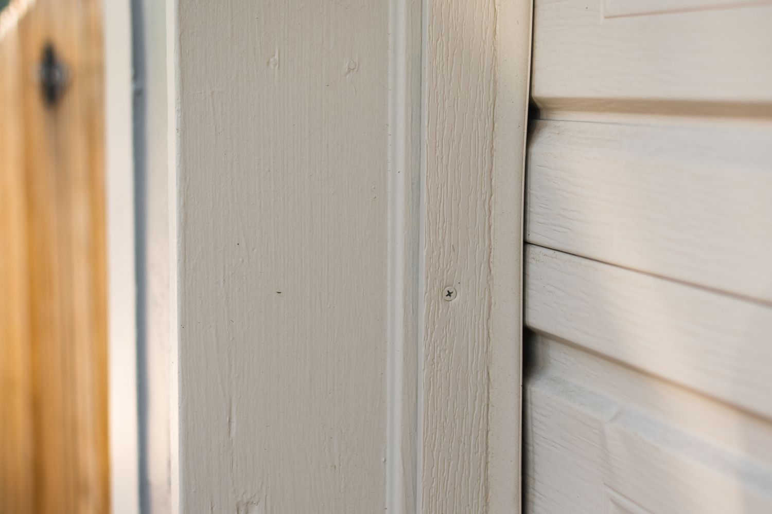 Off-white garage door with weatherstripping vinyl installed to wood door side molding 