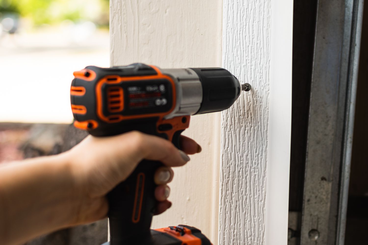 Vinyl door stop with integrated weatherstrip drilled to wood molding in front of garage