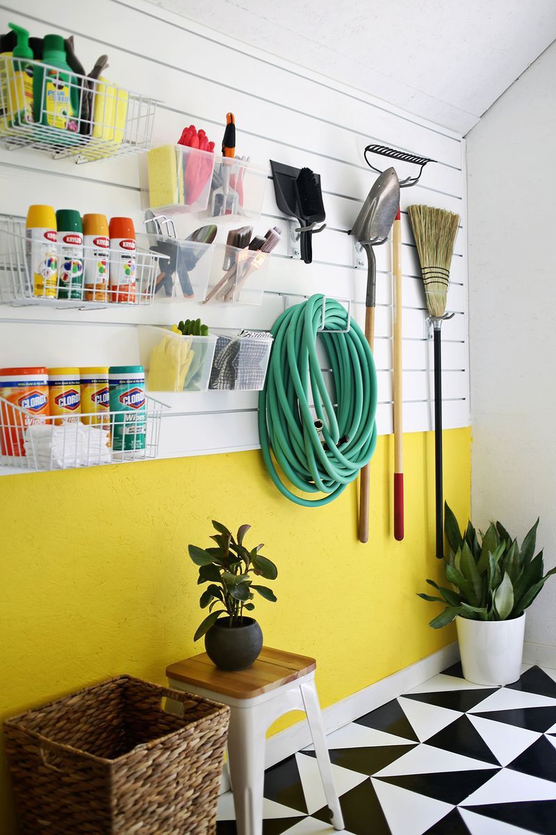 An organized garage with yellow lower walls and black and white flooring.