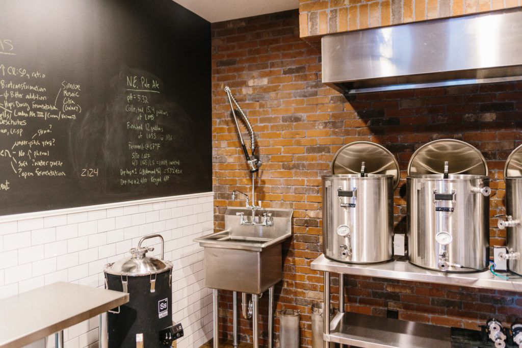 Beer brewing equipment against a brick wall.