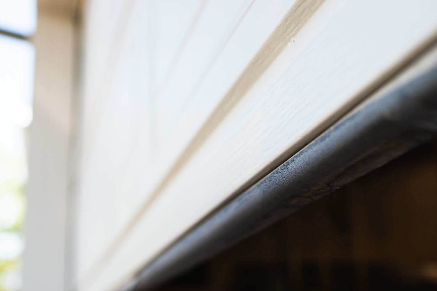 White garage door with a bottom seal with a black strip of rubber closeup