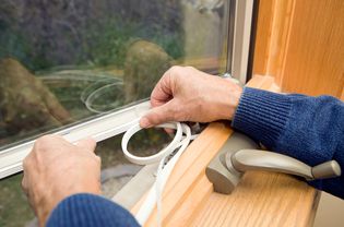 Person applying weatherstripping to windows